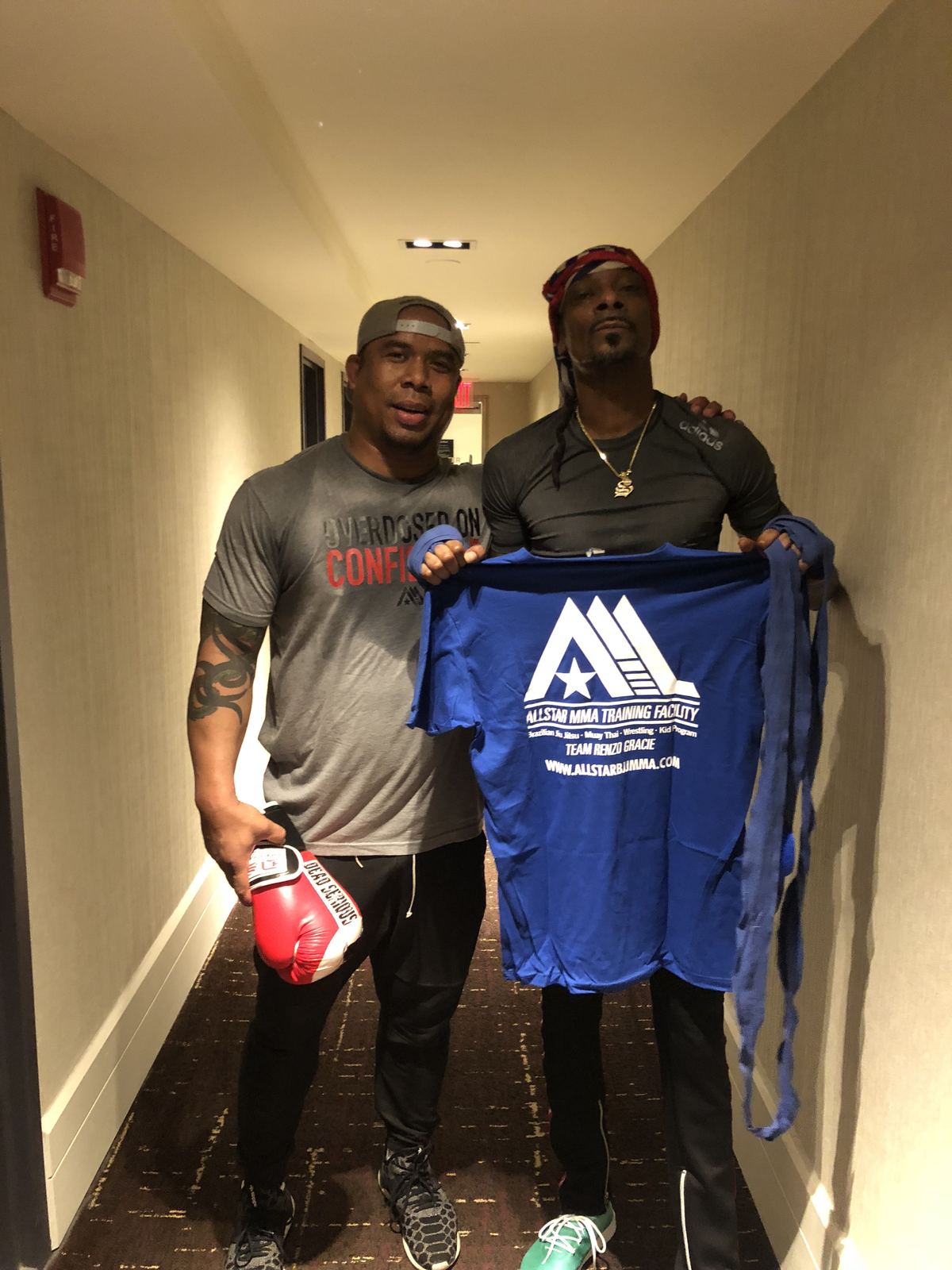 Jamal Patterson with a friend, holding up an AllStar MMA Training Facility shirt