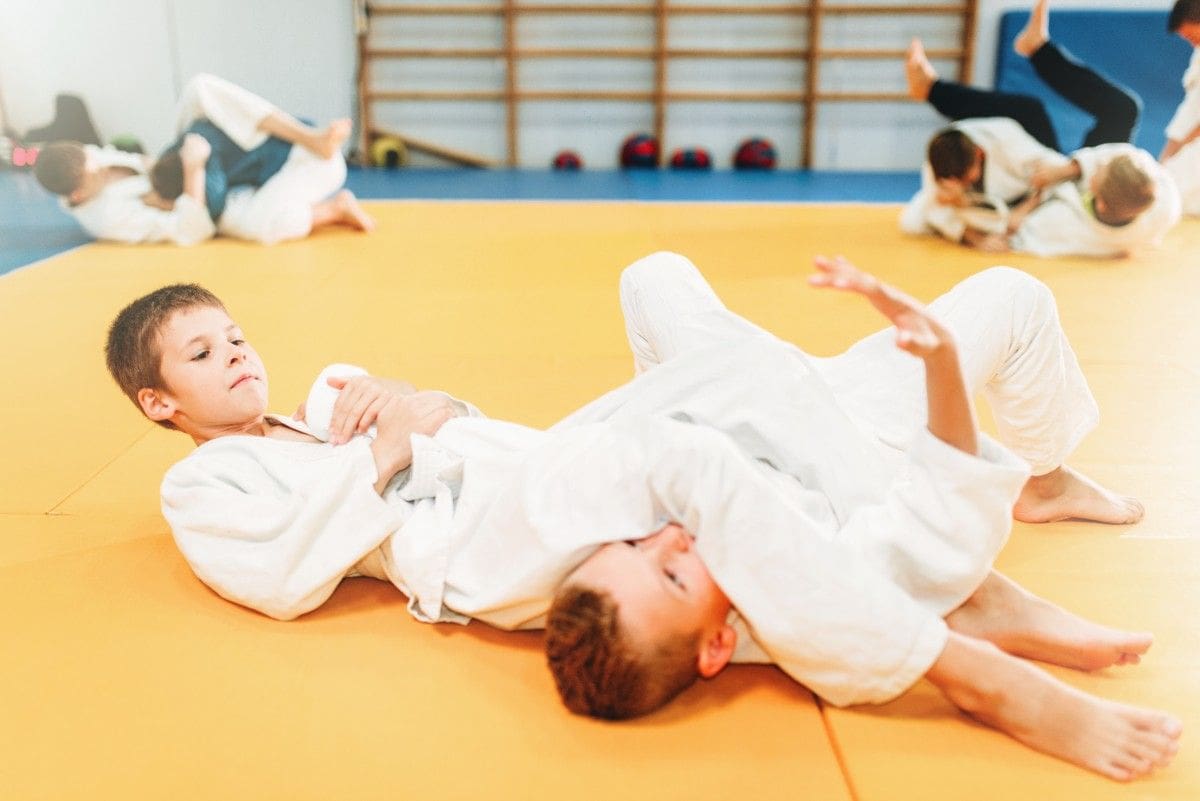 Preschool jiu jitsu students practicing basic grappling drills on padded mats during class